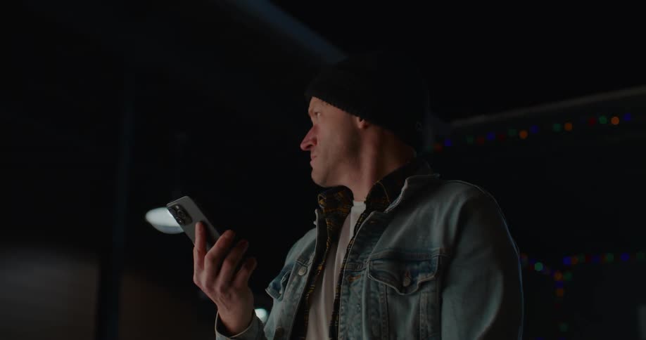 A confused man looking at his cell phone screen