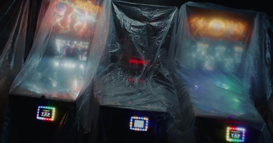 The pinball machines are covered in plastic sheets