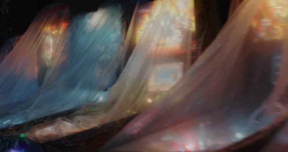 Pinball machines covered in plastic drapes on a dark room