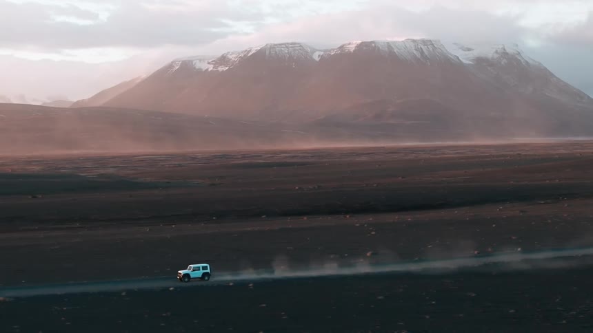 a 4X4 drives on a dirt road past the mountain