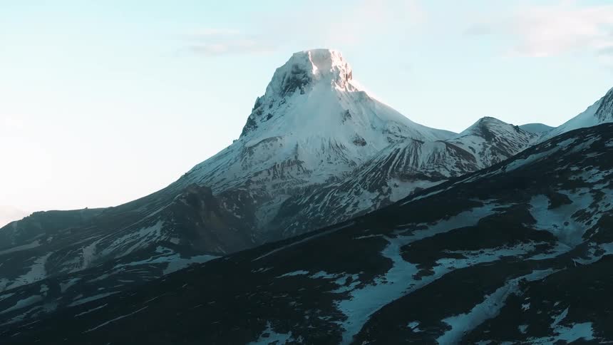 Aerial of a mountain with snow melting during dawn