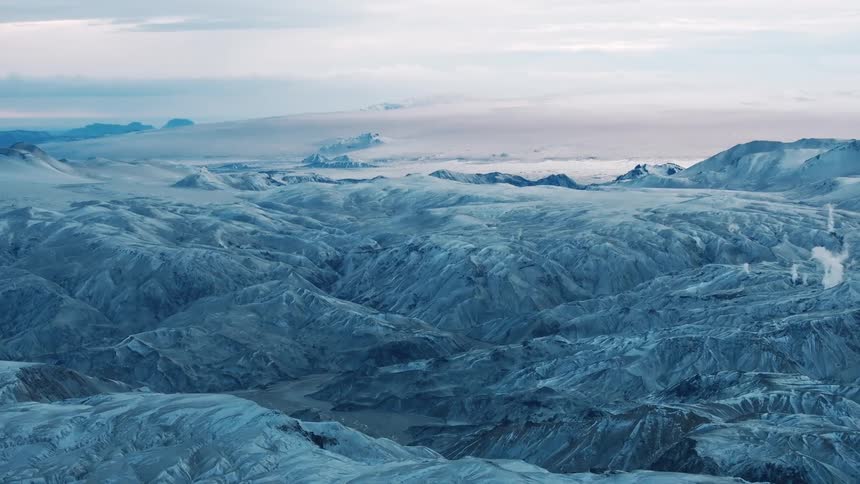 Aerial view of a rugged mountainous landscape covered in snow