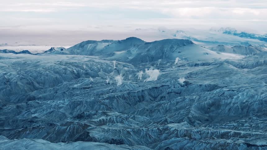 Columns of geothermal steam rises from the rugged slopes of a mountain range