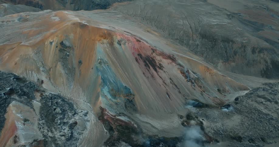 A rugged mountainous terrain with colorful mineral streaks running down the slopes