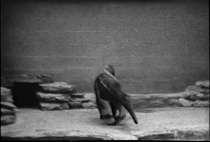 A fake dinosaur walking backwards near a stone wall