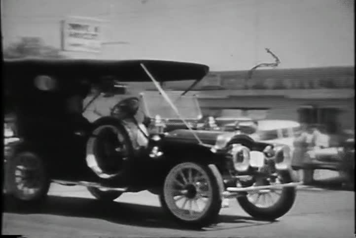 An old-fashioned car driving down the road