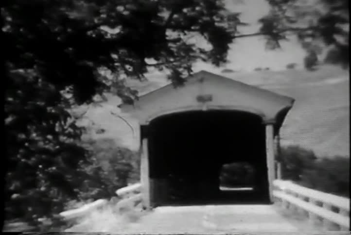 Black and white film of car sitting on a bridge