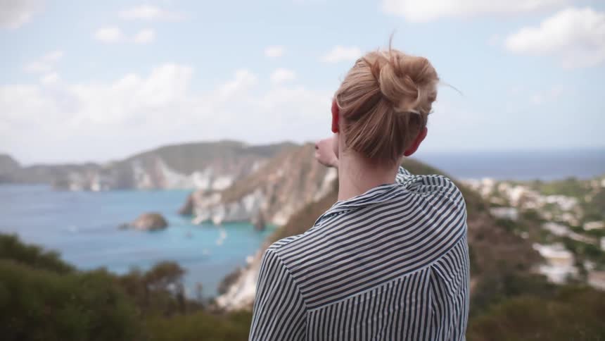 Woman with her back and facing the sea on a mountain peak