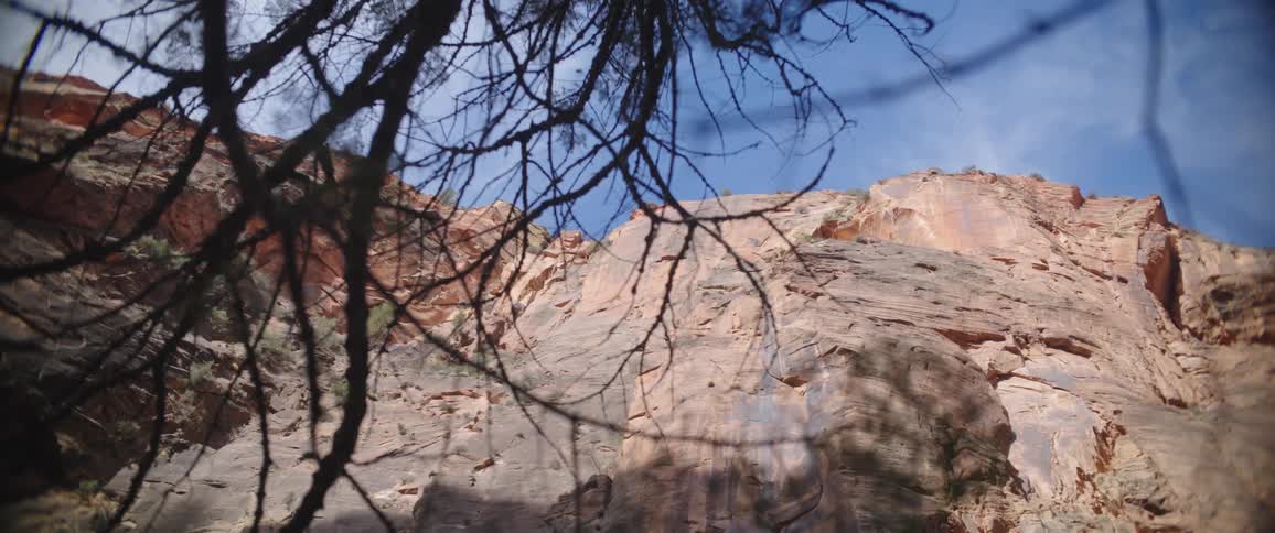 A tall rocky cliff stands beneath a blue sky with a few clouds