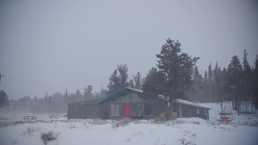 Snow is falling around the cabin