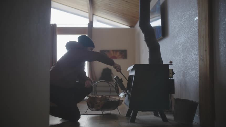 A man uses a poker in a fireplace