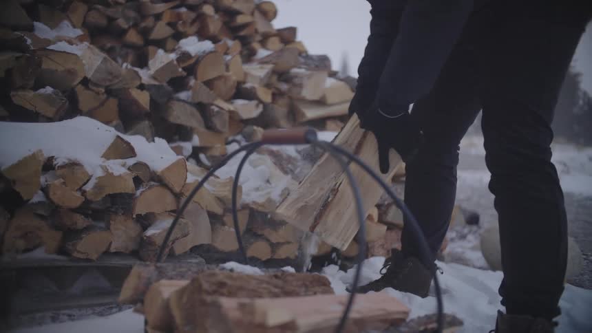 Man picking up chopped firewood and placing it in a bucket