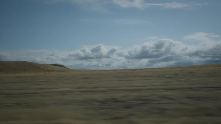 Travelling by a grassy plain with a small hill