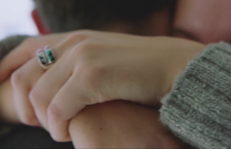 Two people are hugging each other and one of them is wearing two rings on his finger