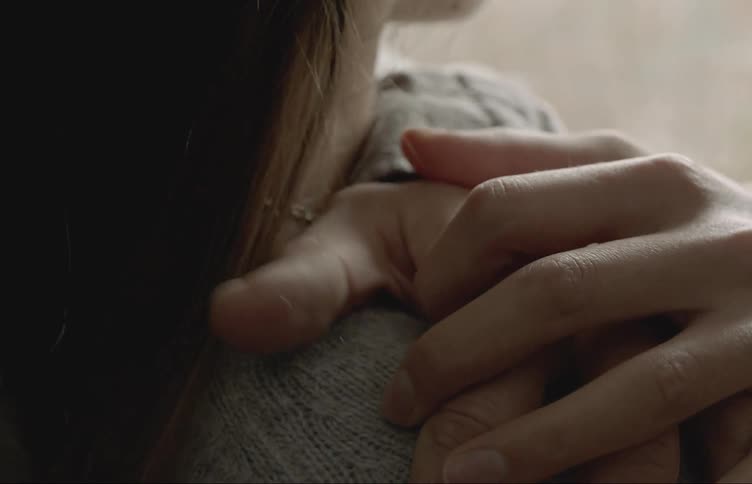 Closeup of a mans hands hugging a woman affectionately