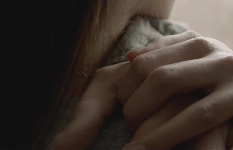 A man and woman hold hands against her shoulder
