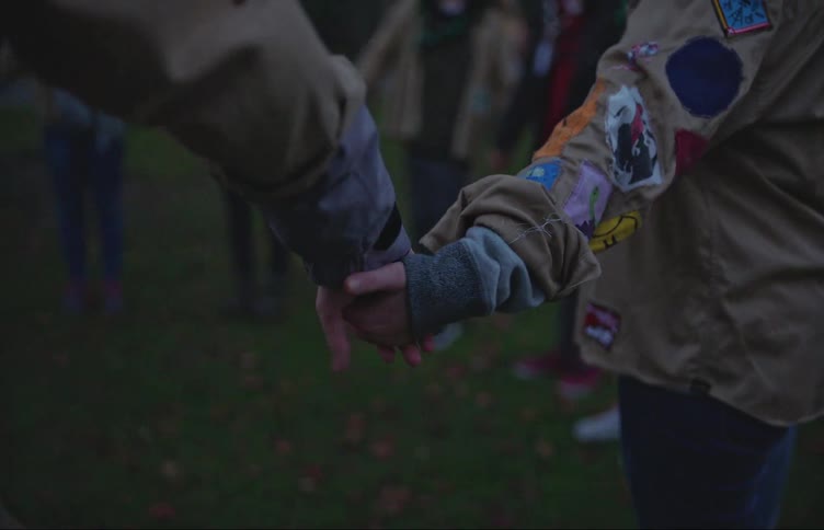 A group of people hold hands outdoors