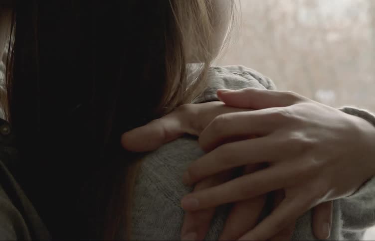A man puts his arm around a woman as they stand outside in winter