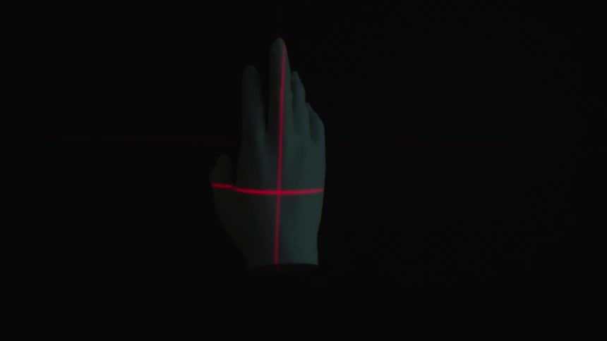 A mannequins hand rotating in a dark room with an infrared laser