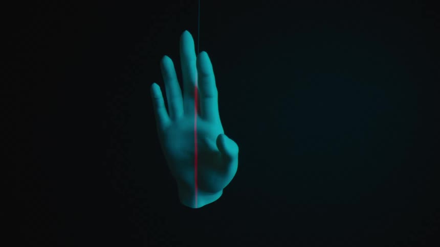A hand illuminated by a blue light in a dark room
