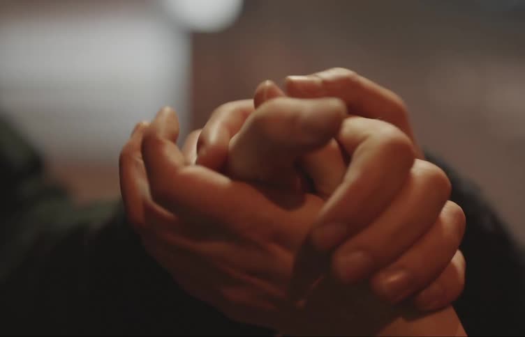 A closeup image of two peoples holding hands in the city