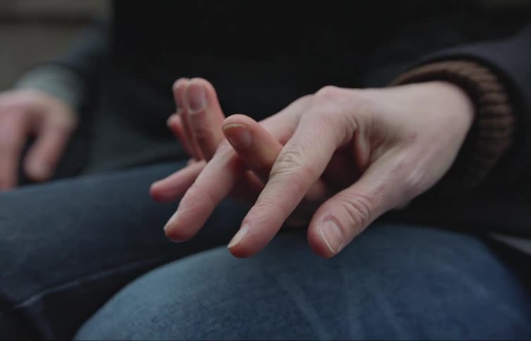 Two peoples hands are intertwining and holding each other on top of a leg wearing jeans