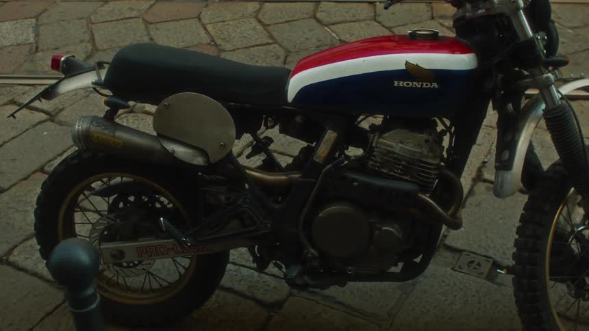 A small parked motorcycle with red with white and blue colors