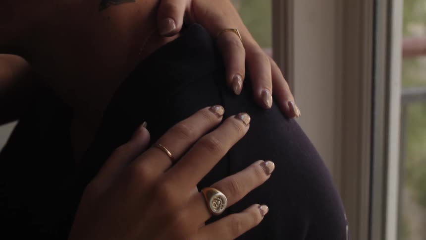 A female hand with rings on a mans shoulder