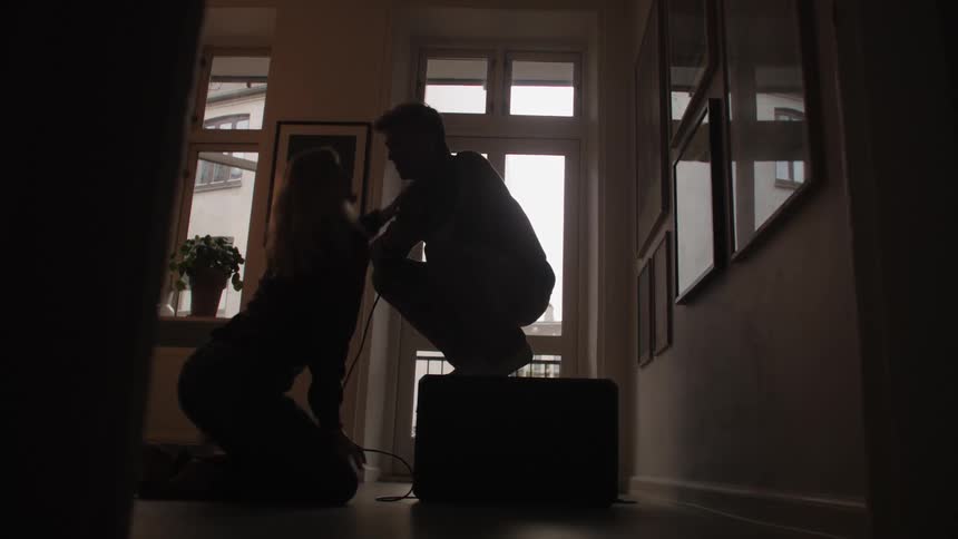 A man and a woman share a kiss in a house