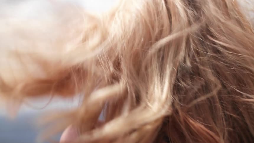 Blonde woman with hair blowing in the wind takes pictures with a smartphone