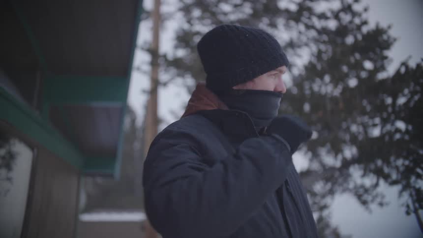 A man bundled up for winter weather looks around outdoors