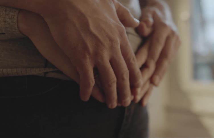 Mans hands hugging his pregnant wifes belly