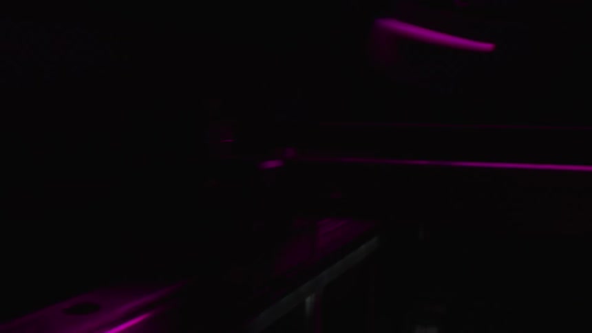 Close up of the moving rails of a 3d printer under flashing colorful lights