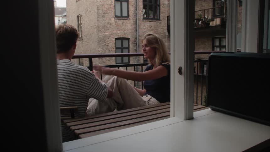 A man and a woman sitting on the balcony of a building while smoking