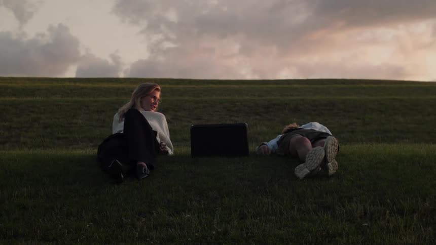 Couple sitting and lying on a lawn in a late afternoon with a purple sky