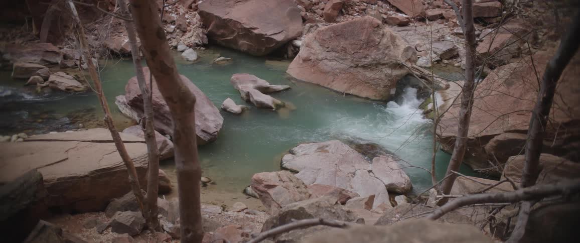 Aerial of a small river between rocky mountains during the day