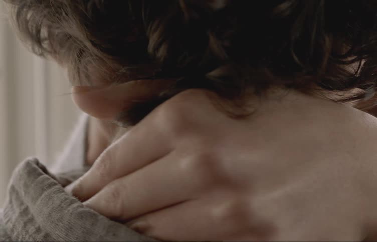 A womans hands go around another persons neck caressing it as they kiss
