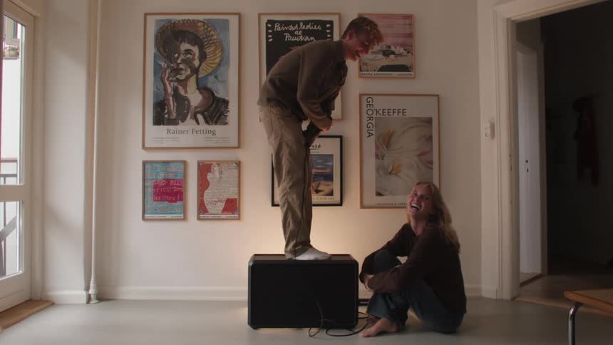 Couple in a room with a man holding the microphone on top of a speaker and his partner sitting and we were smiling a lot