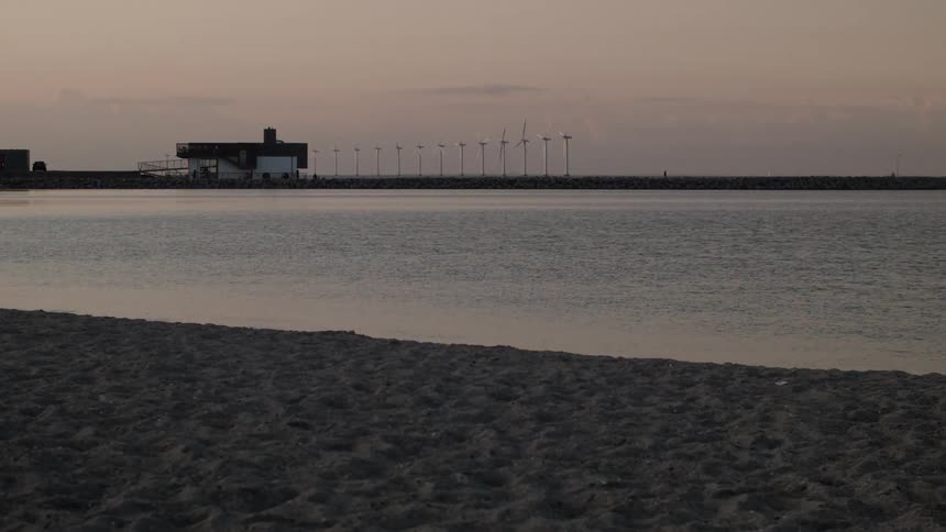 Wind power plants on a beach during dusk