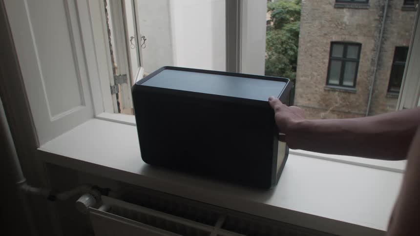 A person turning on a stereo in the window