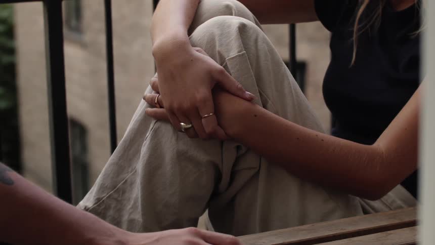 A woman sits outside with a companion as the talk with each other