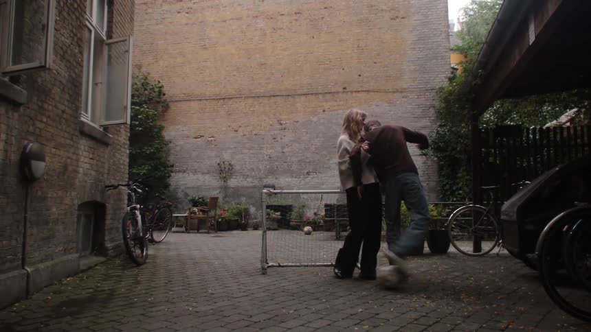 A man and a woman playing football in the backyard on a cloudy day