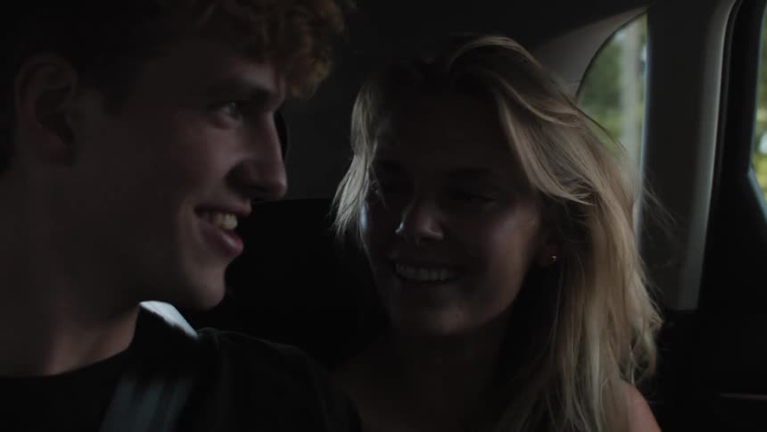 Portrait of a couple sitting in the backseat of a moving car talking smiling