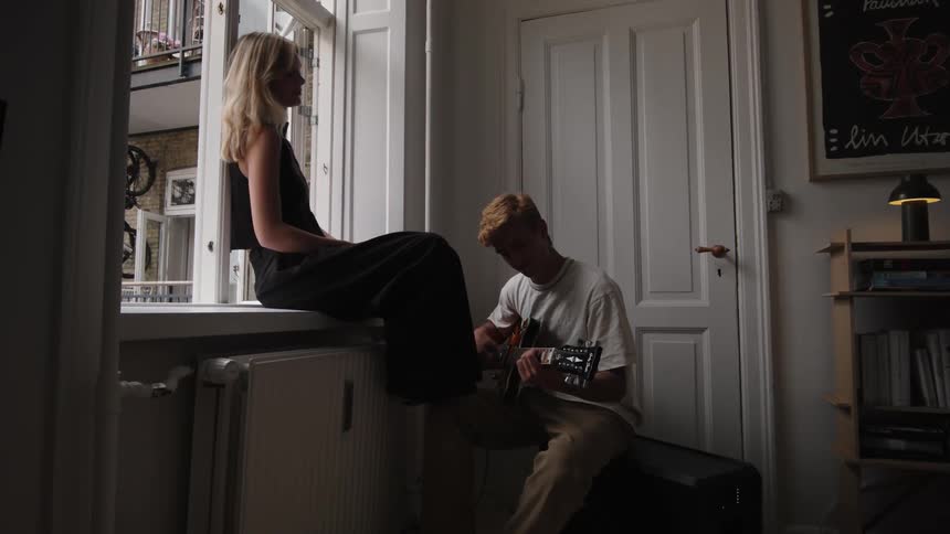 A young man plays a guitar for a woman