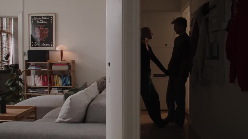 A couple get romantic in the hallway of their apartment