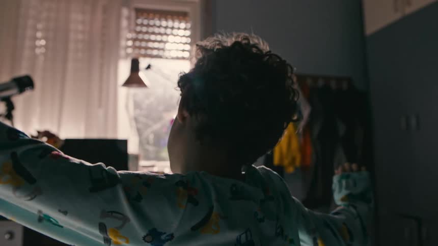 A young boy wakes up and gets out of bed