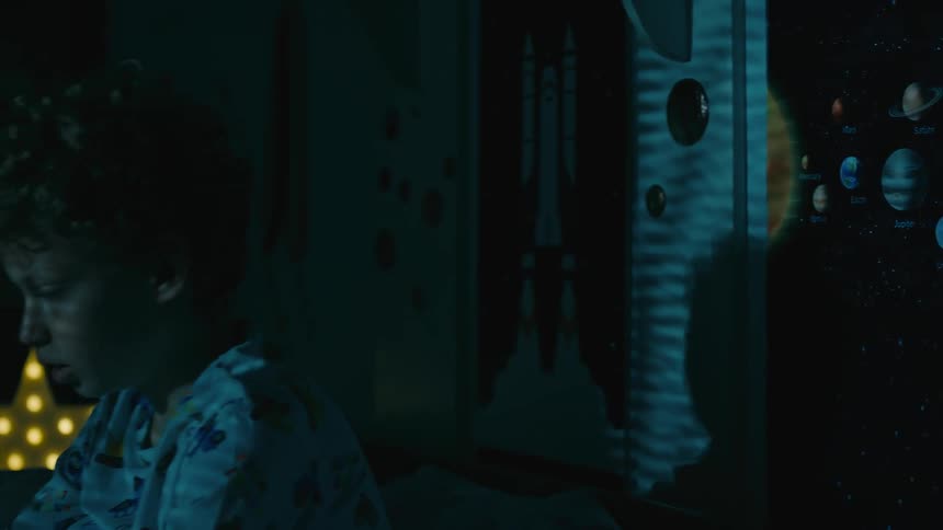 Portrait of a little boy having insomnia and being scared when a shadow passes through his room at night