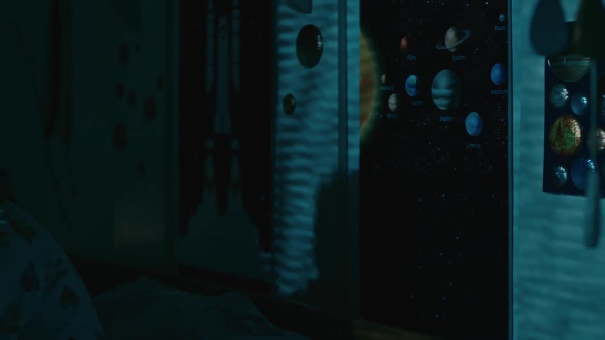 Little boy in his room at night waiting for the background and scared when a shadow passes in front of him