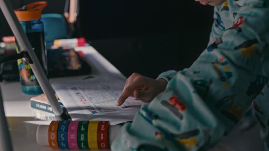 A young boy reads and reviews his worksheet before walking away