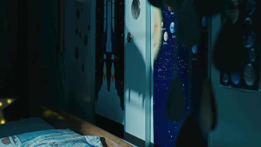 A male child playing with an helicopter toy while sitting on the bed at night